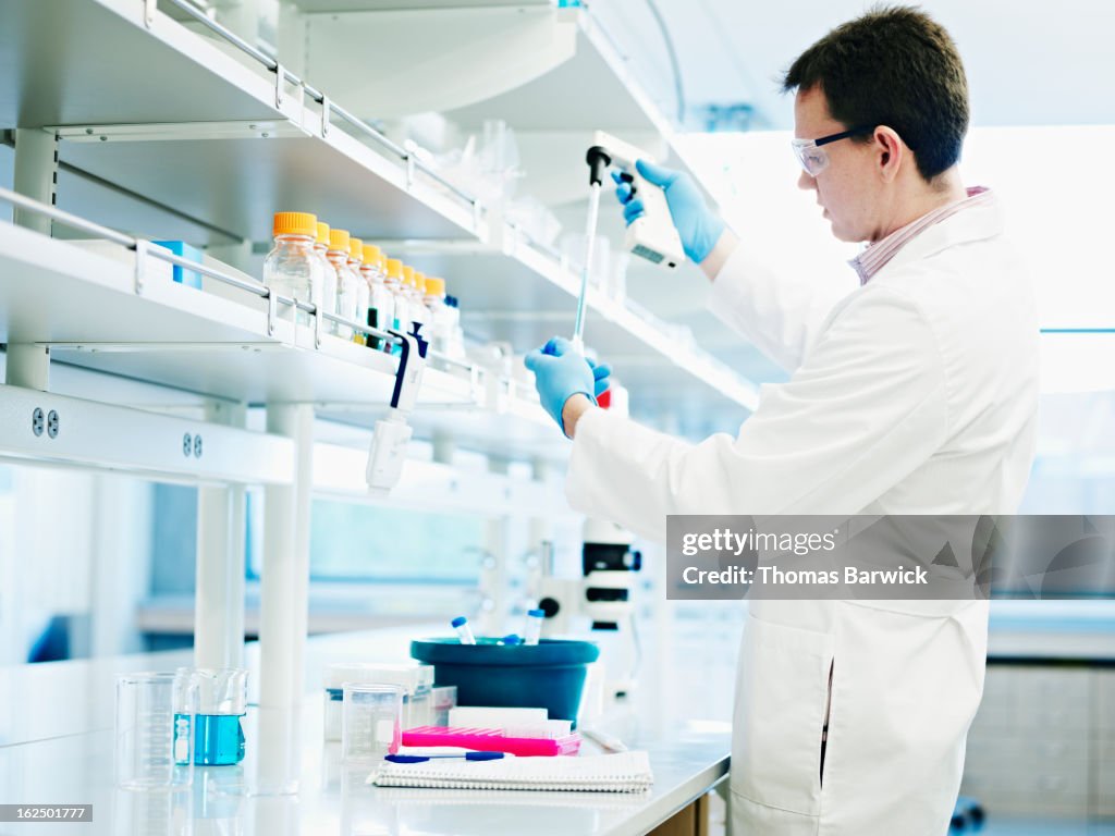 Scientist filling test tube with pipette