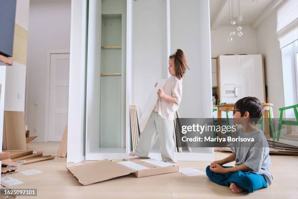 a boy and a girl collects a closet in a bright room at home. - cleaning up after party stock pictures, royalty-free photos & images