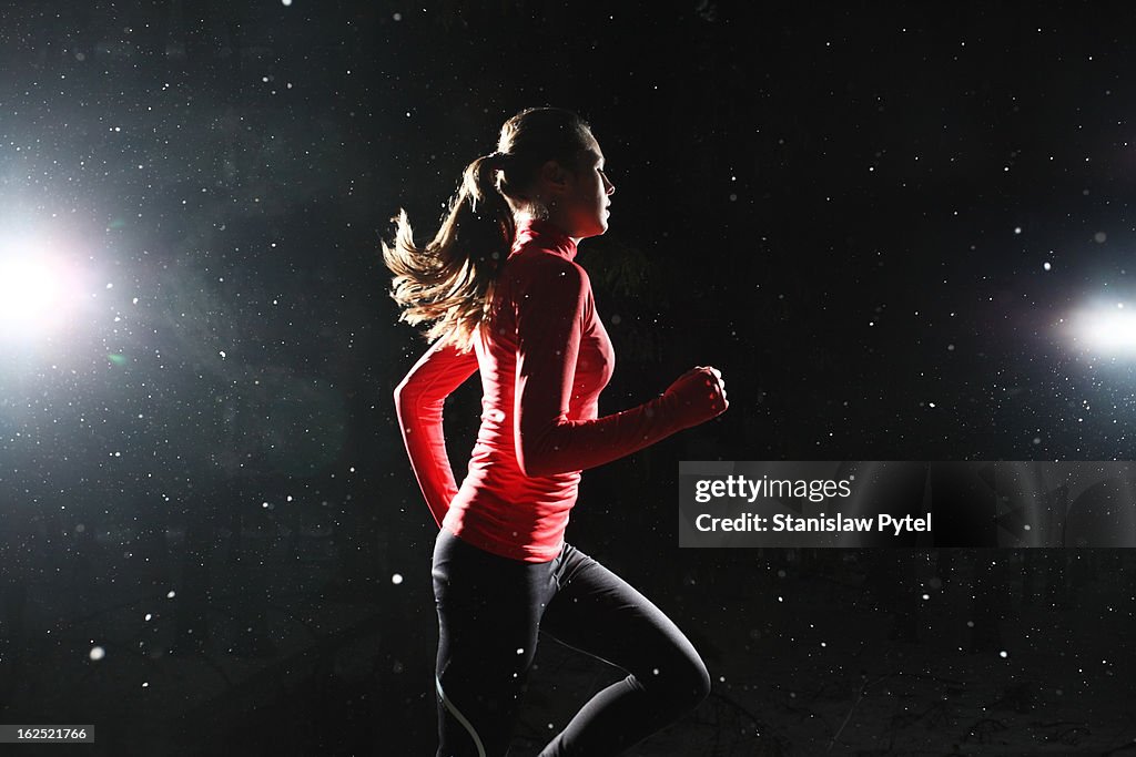 A girl running at night surrounded by snowflakes