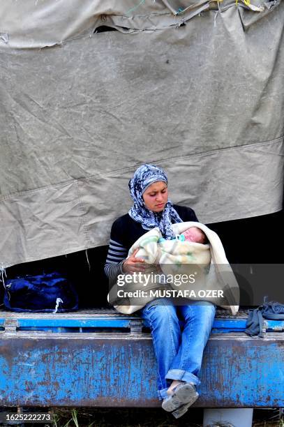 Syrian woman who fled the unrest in Syria holds her baby at a makeshift camp in the northern city of Idlib, near the Turkish village of Guvecci in...