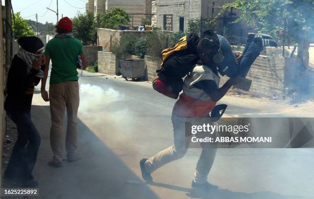 Palestinian medic evacuates a female protester who was hit in the head by a tear gas canister fired by Israeli soldiers during clashes following a...