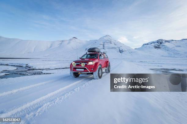 red truck driving on fresh snow, iceland - suv stockfoto's en -beelden