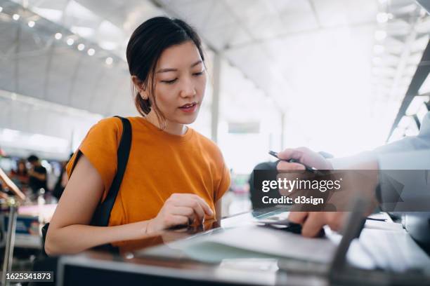 young asian woman travelling by airplane and doing check-in at airline check-in counter at airport terminal. business travel. travel and vacation concept - emigración-e-inmigración fotografías e imágenes de stock