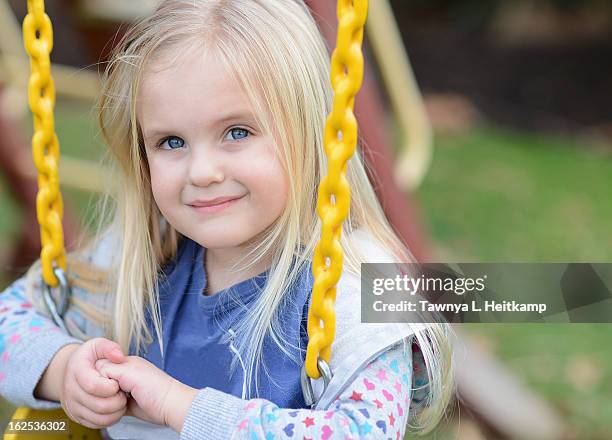 blonde girl smiles on backyard swing hands clasped - fishers indiana stock pictures, royalty-free photos & images