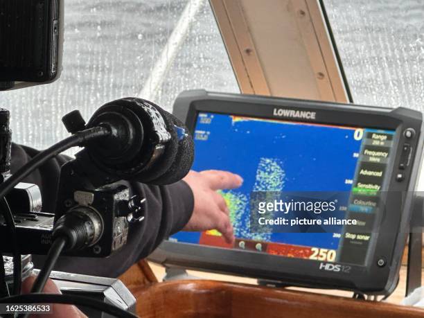 August 2023, Great Britain, Drumnadrochit: Skipper Ali Matheson points to a sonar image of Loch Ness. In Scotland, what is believed to be the largest...