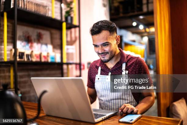 small business owner young man using laptop at a coffee shop - family business restaurant stock pictures, royalty-free photos & images