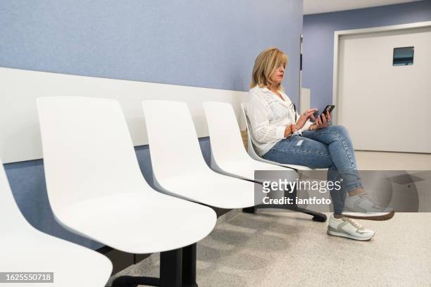 senior woman using mobile phone in waiting room. - office visit stock pictures, royalty-free photos & images