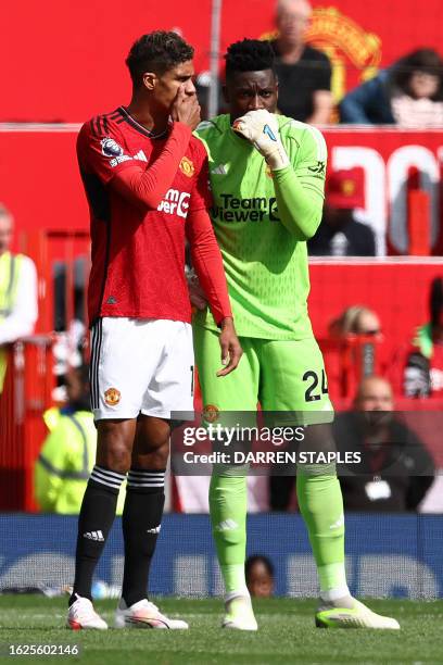 Manchester United's Cameroonian goalkeeper Andre Onana whispers to Manchester United's French defender Raphael Varane during the English Premier...