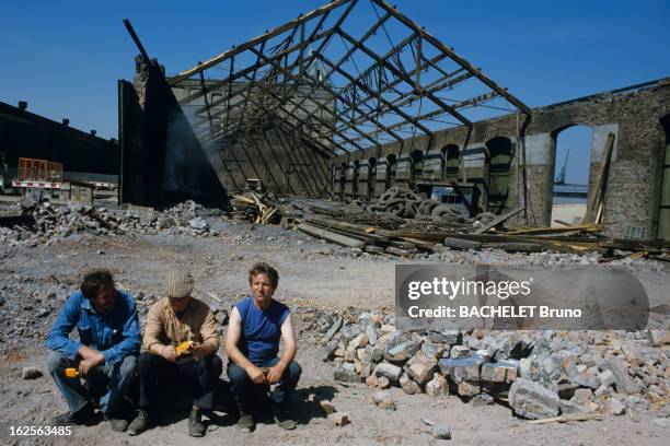 Liverpool. Liverpool - 6 Juin 1985 - Reportage sur la ville de Liverpool: le quartier des docks avec les usines en ruine, 3 hommes assis au premier...