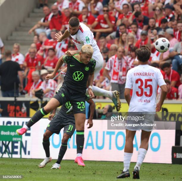 Jeff Chabot of Cologne jumps onto Jonas Wind of Wolfsburg during the Bundesliga match between 1. FC Koeln and VfL Wolfsburg at RheinEnergieStadion on...