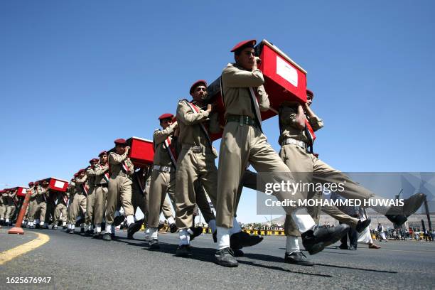 Yemeni military policemen carry the coffins of pro-regime police officers who were killed in recent clashes with gunmen loyal to dissident tribal...