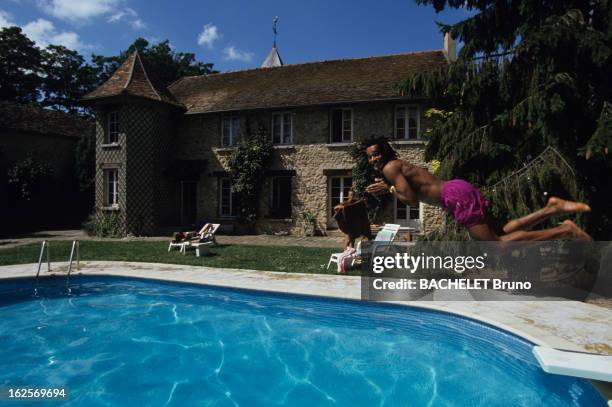 Yannick Noah At Home In Nainville Les Roches. A Nainville -les -Roches, devant sa maison, Yannick NOAH en maillot de bain plongeant du sautoir de sa...