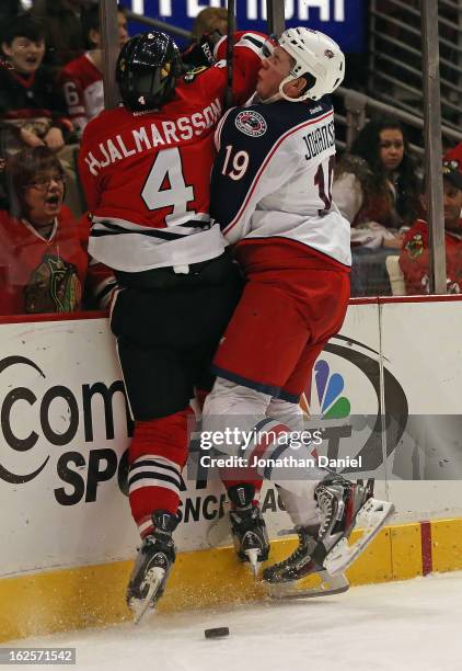 Niklas Hjalmarsson of the Chicago Blackhawks and Ryan Johansen of the Columbus Blue Jackets collide against the boards at the United Center on...