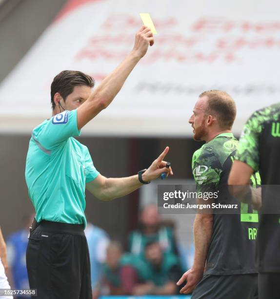 Referee Matthias Joellenbeck shows a yellow card to Maximilian Arnold of Wolfsburg during the Bundesliga match between 1. FC Koeln and VfL Wolfsburg...