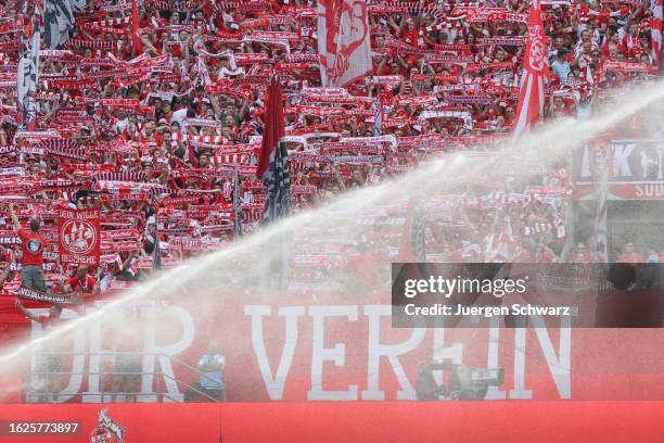 Supporters of Cologne lift their scarfs while the lawn is artificially watered prior to the Bundesliga match between 1. FC Koeln and VfL Wolfsburg at...