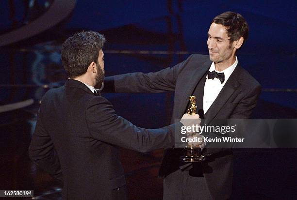 Presenter Ben Affleck greets filmmaker Malik Bendjelloul and Simon Chinn as they accept the Best Documentary - Feature award for "Searching for Sugar...