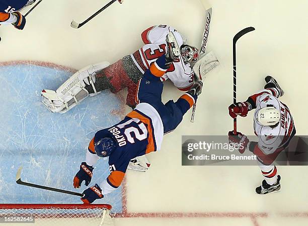 Kyle Okposo of the New York Islanders flies over Cam Ward of the Carolina Hurricanes at the Nassau Veterans Memorial Coliseum on February 24, 2013 in...