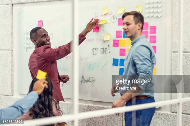 african american and caucasian employees writing ideas on sticky notes and brainstorming - scrum 個照片及圖片檔