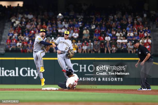 Willy Adames of the Milwaukee Brewers attempts to turn a double play on Ezequiel Duran of the Texas Rangers in the third inning at Globe Life Field...