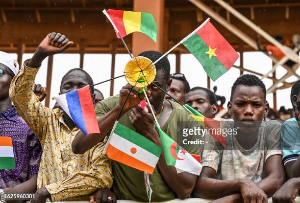 Supporter of Niger's National Council for Safeguard of the Homeland holds national flags of Mali, Burkina Faso, Algeria, Niger and Russia as they...