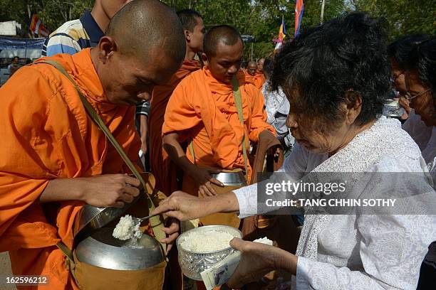 Cambodian people offer food to Buddhist monks during the Meak Bochea Buddhist celebration at the Oddong mountain in Kandal province, some 40...