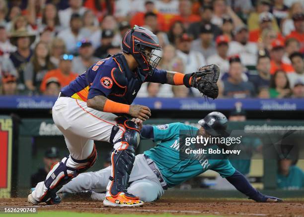 Teoscar Hernandez of the Seattle Mariners scores in the third inning as Martin Maldonado of the Houston Astros awaits the throw at Minute Maid Park...