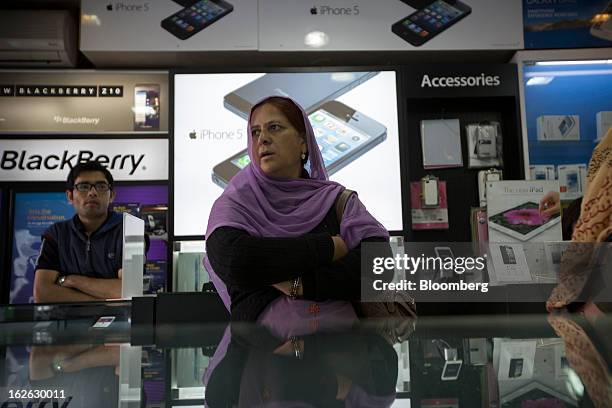 Woman stands as Apple Inc. IPhone 5 and Blackberry Z10 advertisements are displayed in store in Connaught Place in New Delhi, India, on Saturday,...