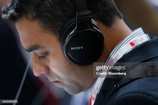 Visitor wears branded headphones as he listens to a Sony Corp. Xperia Z smartphone at the Mobile World Congress in Barcelona, Spain, on Monday, Feb....