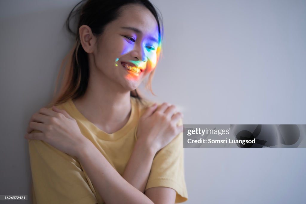 Asian woman with neuro disorder embrace herself and laughing with nothing in mind with sign of divergent emotion light on her face..