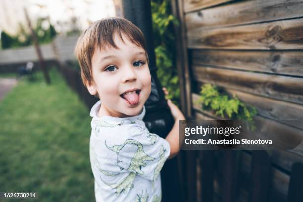 smiling boy showing tongue at the playground, looking at camera - taquiner photos et images de collection