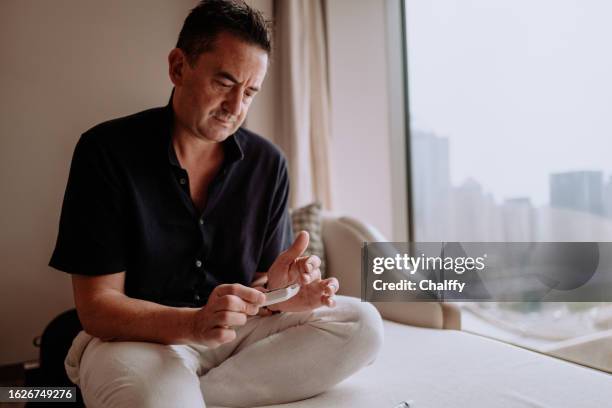 l’homme teste l’acide urique et la glycémie à la maison pour éviter l’hyperuricémie (goutte) - kit pour tester photos et images de collection