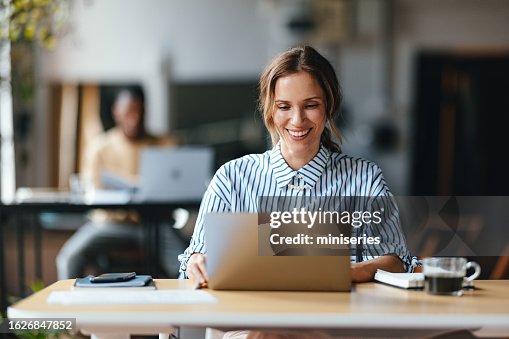 Una hermosa y feliz mujer de negocios rubia trabajando en su computadora Una hermosa y feliz mujer de negocios rubia trabajando en su computadora