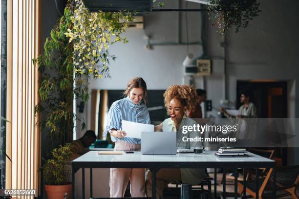 zwei glückliche schöne blonde geschäftsfrauen, die mit ihrem computer im büro arbeiten - reading female stock-fotos und bilder