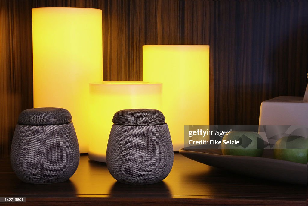 Still-life of vessels,candles and apples on shelf