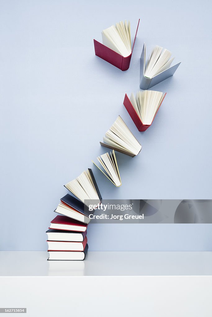 Books taking off from a stack