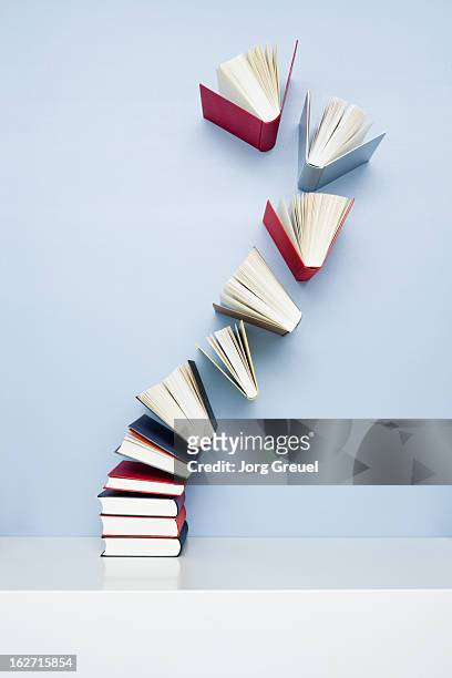 books taking off from a stack - livre photos et images de collection
