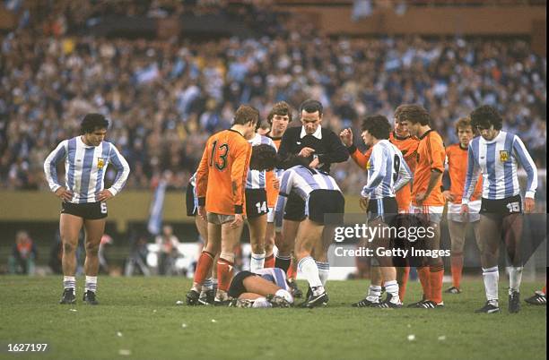 Gonella, the referee of Italy looks at his watch as an Argentinan player lies injured on the ground during the World Cup Final match between...