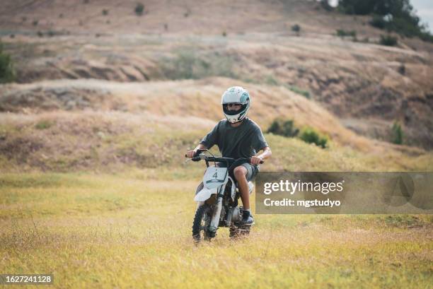 motorradrennfahrerjunge bereitet sich auf motocross-rennen vor. - route moto stock-fotos und bilder