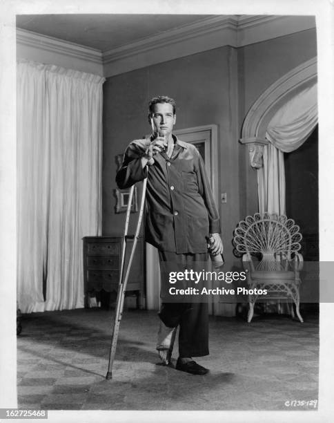 Paul Newman with drink and crutch in publicity portrait for the film 'Cat On A Hot Tin Roof', 1958.