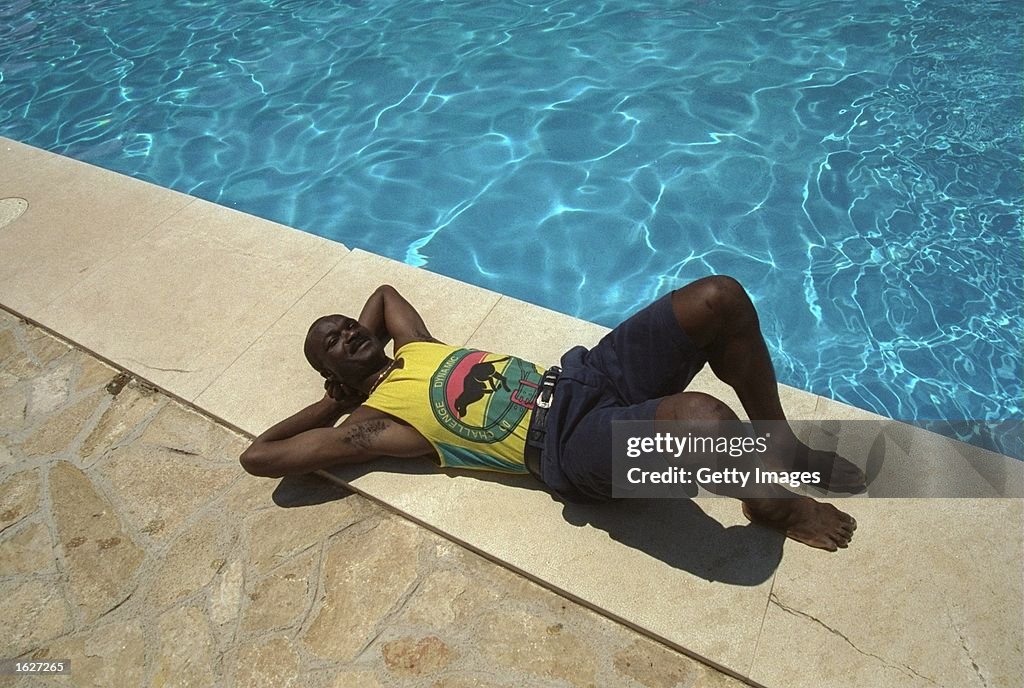 Roger Milla striker of the Cameroon team relaxes by a swimming pool