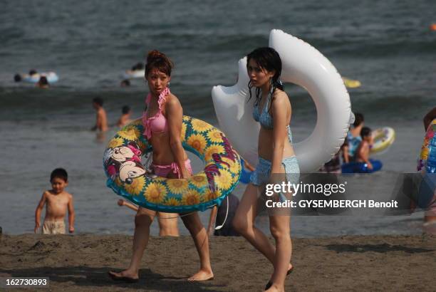 The Japanese Riviera. Deux Japonaises en maillot de bain, bouée à la main, marchant sur la plage de KATASE-ENOSHIMA à une centaine de kilomètres de...