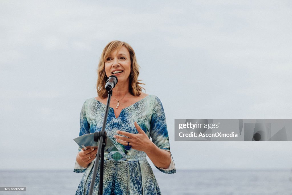 Senior woman gives speech above sea