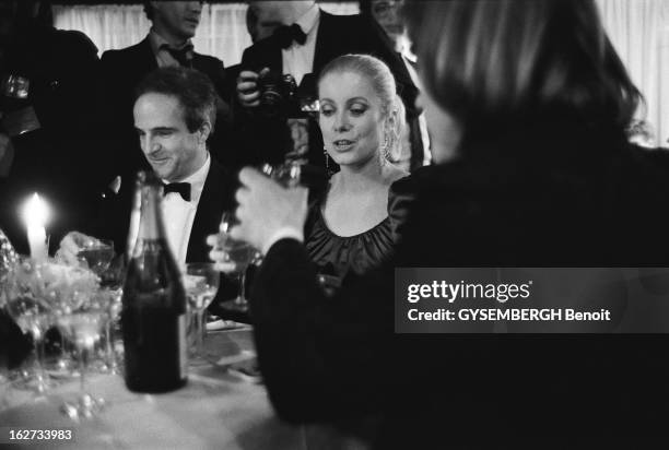 The 7Th Night Of Cesar 1981. Catherine DENEUVE souriante , assise entre François TRUFFAUT et Gérard DEPARDIEU , tous trois à table un verre àla main...