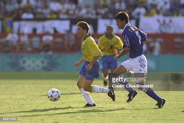 Juninho of Brazil and Hideto Suzuki of Japan compete for the ball during the match against Japan at the Centennial Olympic Games in Atlanta at the...
