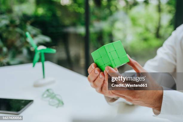 hands of businessman with green puzzle cube at desk - rubiks kub bildbanksfoton och bilder