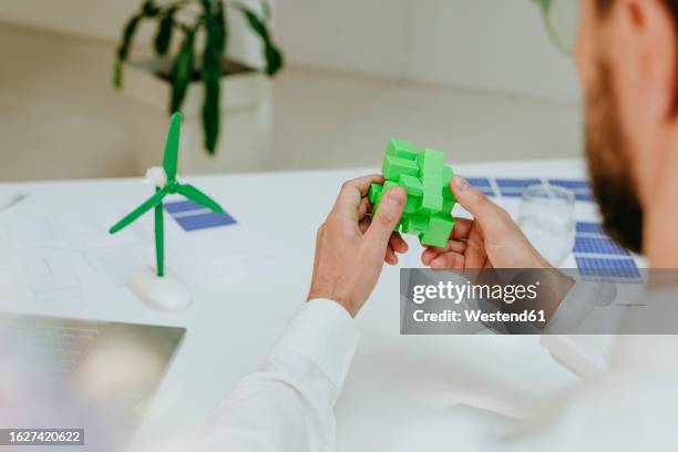 businessman solving green puzzle cube at desk - rubiks kub bildbanksfoton och bilder
