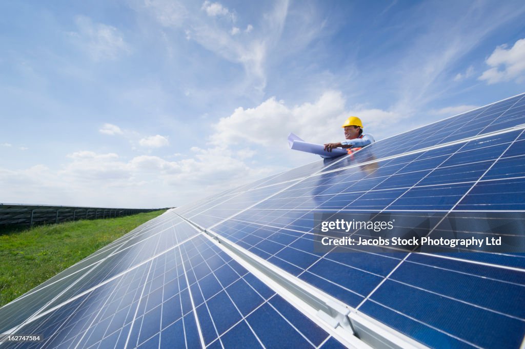 Mixed race man with blueprints checking solar panels