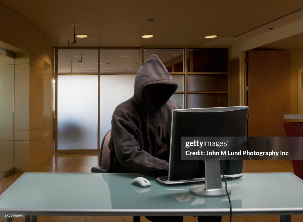 Caucasian man in hoody sitting at office desk