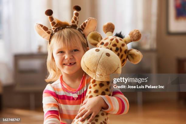 caucasian girl wearing giraffe headband and holding toy giraffe - portrait of a young girl with gappy teeth and blond hair stock pictures, royalty-free photos & images