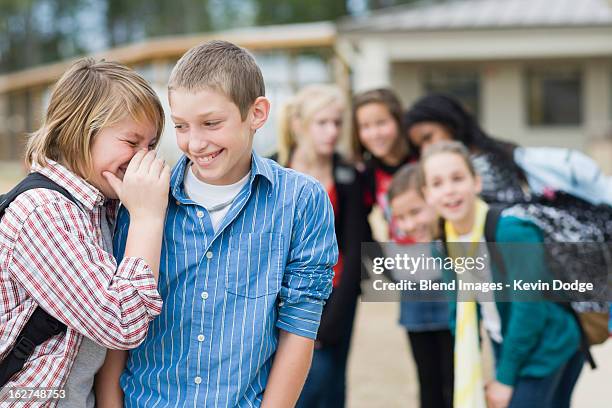 caucasian school boys whispering together - veralbern stock-fotos und bilder